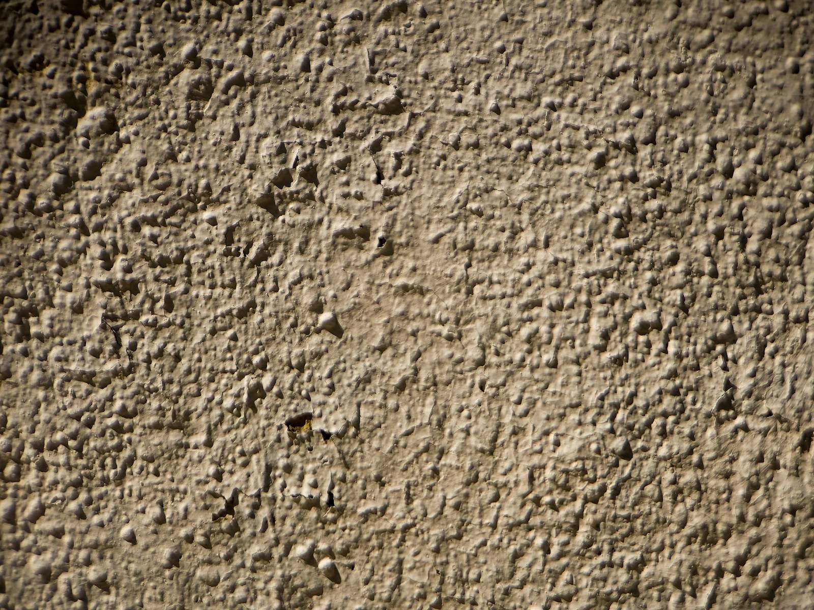 Close-up van een beige gevelpleister met grove korrel